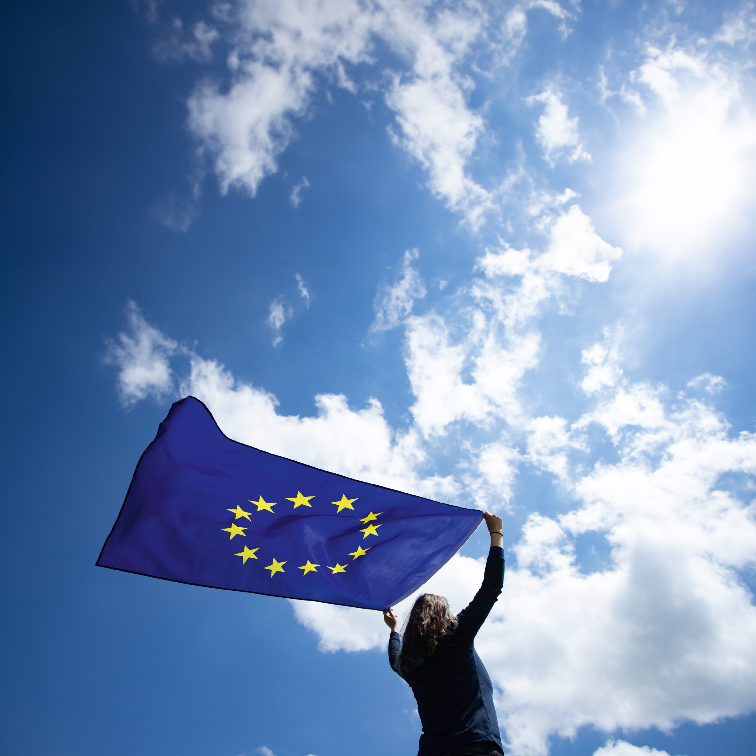 Frau mit Europaflagge unter blauem Himmel